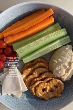 a plate with carrots, celery, crackers and other food items