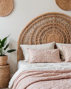 a bed with pink sheets and pillows next to two wicker baskets on the wall