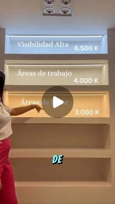 a woman pointing to the wall in front of a sign that says area de trabio 4, 000 k