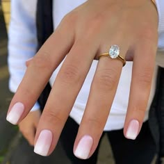 a close up of a person's hand with a ring on their finger and an engagement ring in the other hand