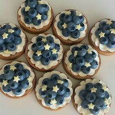 twelve blueberry cupcakes with white frosting and stars on top are arranged in a circle