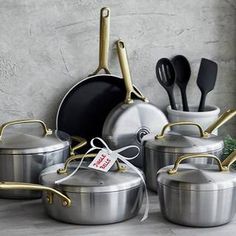 an assortment of pots and pans are on the table with utensils in them