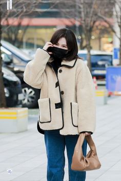 a woman is walking down the street talking on her cell phone and wearing a coat