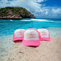 two pink and white hats sitting on top of a sandy beach next to the ocean