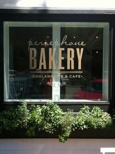 the window of a bakery with plants growing out of it's windowsills