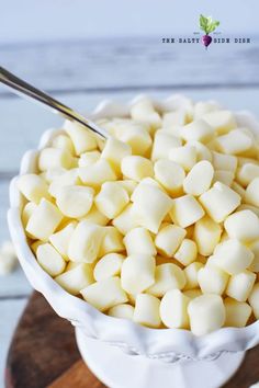 a white bowl filled with marshmallows on top of a wooden cutting board