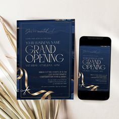 an open grand opening card and phone next to some gold ribbon on a white background