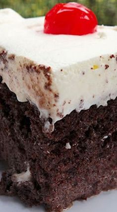 a piece of chocolate cake with white frosting and a cherry on top