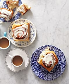 two plates with pastries on them next to cups of coffee