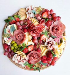 a platter filled with lots of different types of cheeses and fruit on top of each other