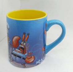 a blue and yellow coffee mug with cartoon characters on it