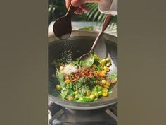 someone is sprinkling seasonings on a salad in a skillet