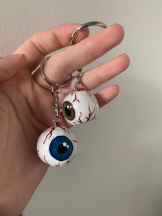 a hand holding two key chains with fake eyeballs on them