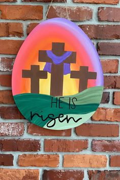 a paper plate with the words he is risen on it hanging from a brick wall