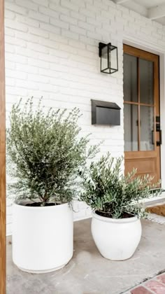 two white planters sitting on top of a porch next to a brick building with the words spring porch inspiration