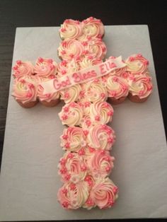 a cross made out of cupcakes on top of a white paper towel with pink frosting