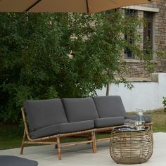 a couch sitting on top of a wooden floor next to a table with an umbrella over it