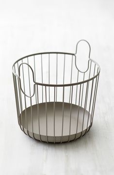 a wire basket with a plate in the middle on a white tableclothed surface