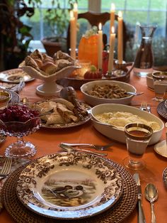 a table with plates, silverware and candles on it