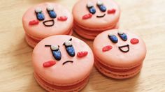 four decorated cookies with faces on them sitting on a wooden counter top, one is pink and the other is blue