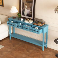 a blue console table with two drawers and a painting on the wall in front of it