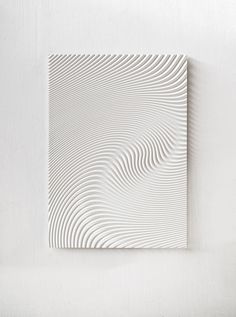 a white square with wavy lines in the center on a white wall above it is a plant