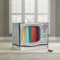 an old television with the colors of the tv on it's screen is sitting in front of two windows