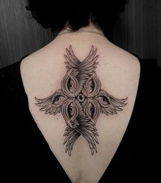 the back of a woman's neck with an intricate tattoo design on her shoulder