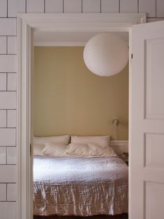 an open door leading to a bed with white sheets and pillows in a bedroom area