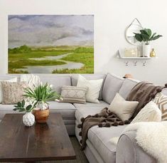 a living room with couches, tables and potted plants in the center area