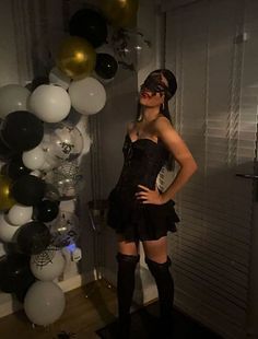 a woman standing in front of balloons with her hands on her hips and wearing knee high boots