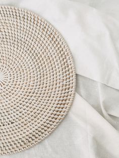 a woven placemat on a bed with white sheets