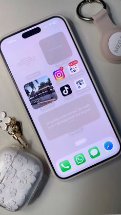 an iphone and keychain sitting next to each other on a table with the phone screen open