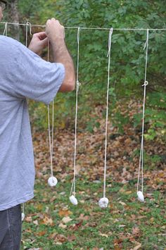 a man standing in front of a forest with lots of white balls hanging from it