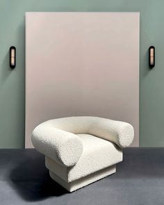 a white chair sitting in front of a wall with two lights on it's sides