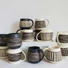 a stack of black and white cups sitting next to each other on top of a table