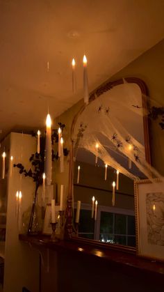 there are many lit candles on the mantle in this room, and one candle is hanging from the ceiling