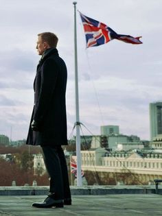 a man standing on top of a roof next to a british flag flying in the background