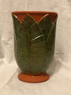 a green plant pot sitting on top of a white sheet