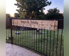 a sign that is on the side of a fence in front of some grass and trees