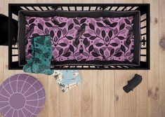 an overhead view of a baby crib with purple and black items on the floor