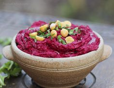 a bowl filled with beet hummus sitting on top of a wooden table