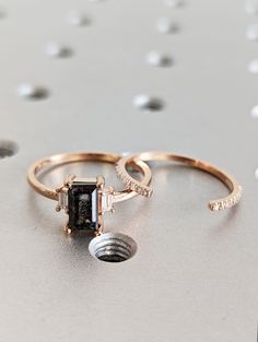 two gold rings with black and white stones on them sitting on top of a table