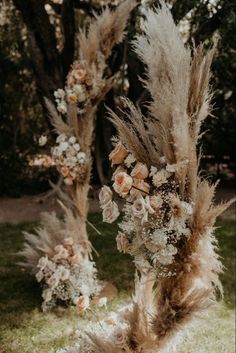 an arrangement of flowers and feathers on display in front of two tall tree stumps