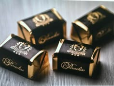 four black and gold candy boxes sitting on top of a table