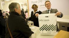 a man holding up a bag with the name john lewis on it while two women look on