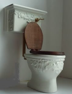 a white toilet with a wooden seat in a bathroom next to a wall mounted shelf