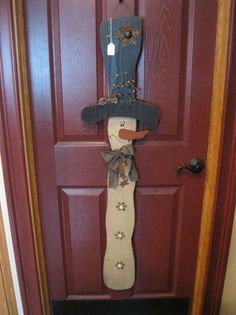 a wooden snowman door hanger on a red front door