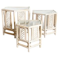 three white wicker side tables with glass tops on each end, set against a white background