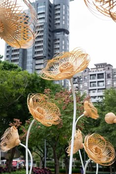 several metal sculptures in the middle of a park with tall buildings behind them and trees on either side